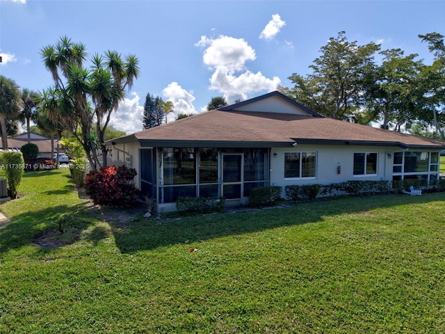 rear view of property with a sunroom, central AC, and a lawn