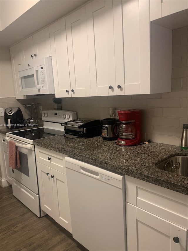 kitchen featuring white appliances, dark stone countertops, dark hardwood / wood-style flooring, and white cabinets