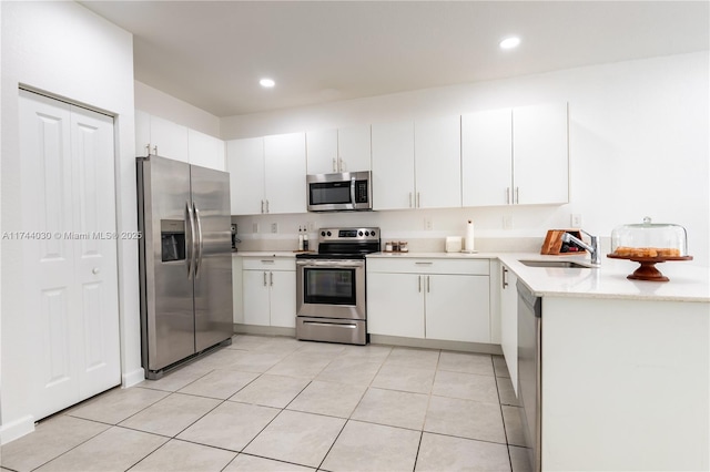 kitchen featuring light tile patterned flooring, appliances with stainless steel finishes, sink, and white cabinets