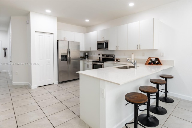 kitchen featuring a breakfast bar, white cabinetry, sink, kitchen peninsula, and stainless steel appliances