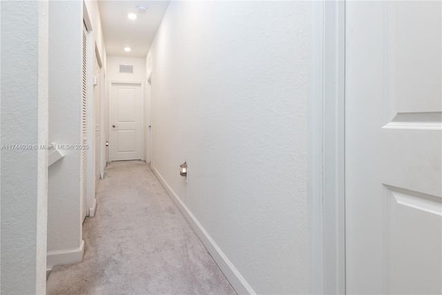 hallway featuring light colored carpet