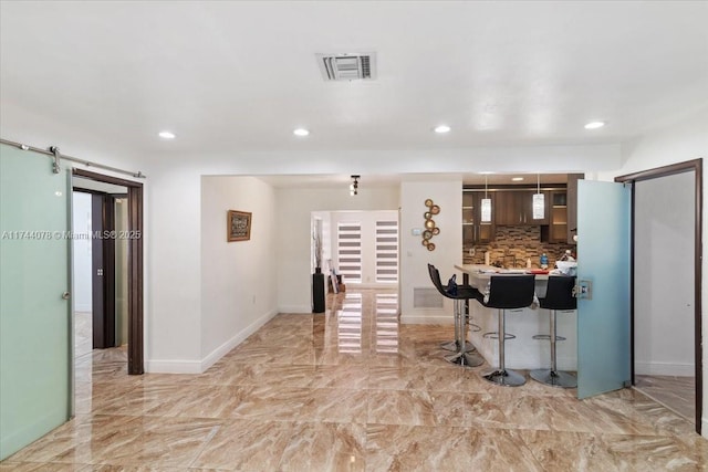 kitchen with pendant lighting, tasteful backsplash, a breakfast bar area, kitchen peninsula, and a barn door