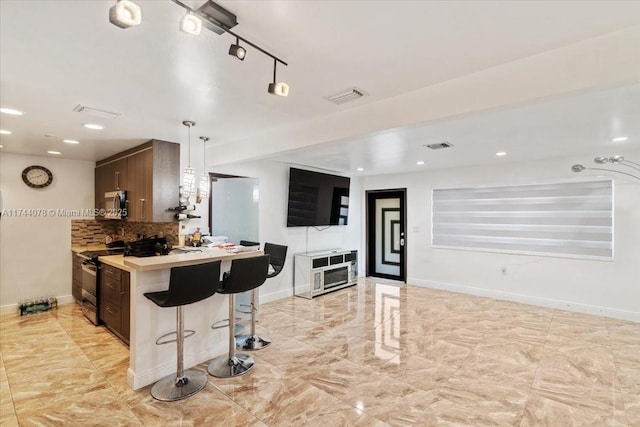 kitchen with a breakfast bar area, tasteful backsplash, dark brown cabinets, kitchen peninsula, and stainless steel appliances