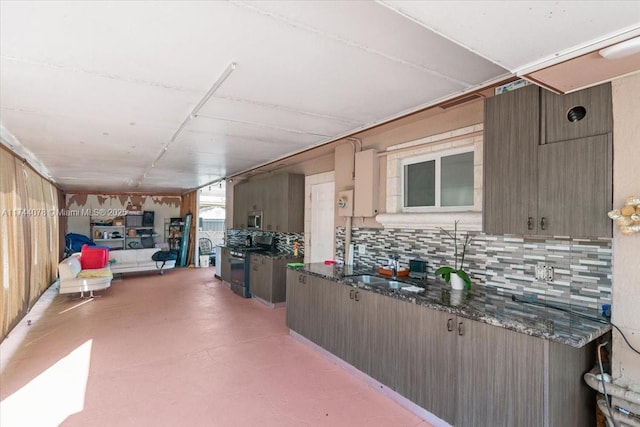 kitchen featuring sink, appliances with stainless steel finishes, backsplash, concrete flooring, and dark stone counters