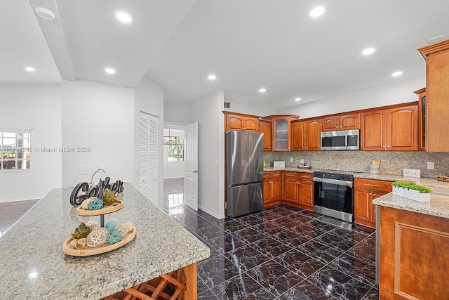 kitchen featuring appliances with stainless steel finishes, light stone counters, and tasteful backsplash