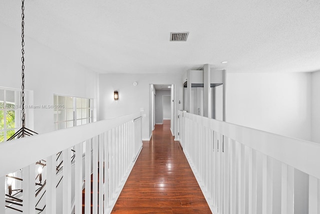 corridor with dark hardwood / wood-style floors and a textured ceiling