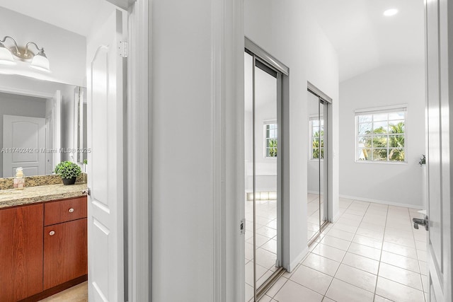 hallway featuring plenty of natural light, vaulted ceiling, and light tile patterned floors