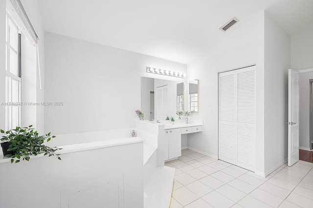 bathroom with a healthy amount of sunlight, tile patterned flooring, a tub to relax in, and vanity