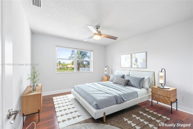 bedroom featuring dark hardwood / wood-style flooring, ceiling fan, and a textured ceiling