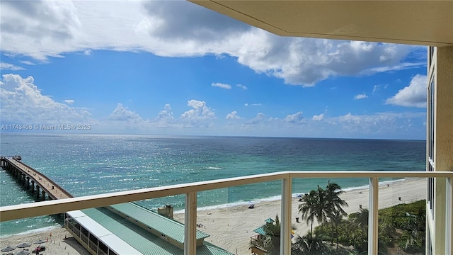 balcony with a water view and a view of the beach