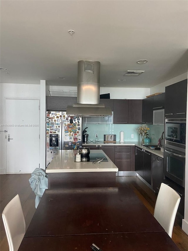 kitchen with a kitchen island, island exhaust hood, dark hardwood / wood-style floors, and appliances with stainless steel finishes