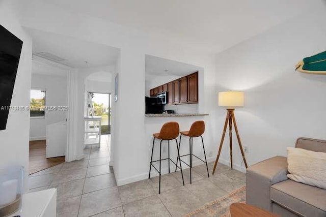 kitchen featuring a breakfast bar, kitchen peninsula, and light tile patterned floors