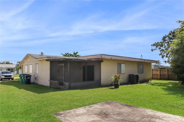 rear view of house with central AC and a lawn