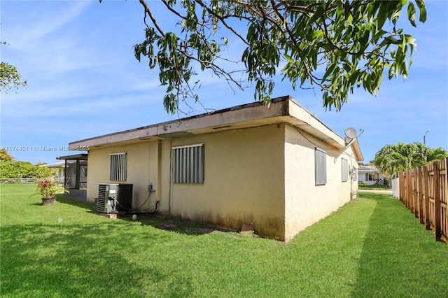 view of side of property featuring central AC unit and a lawn