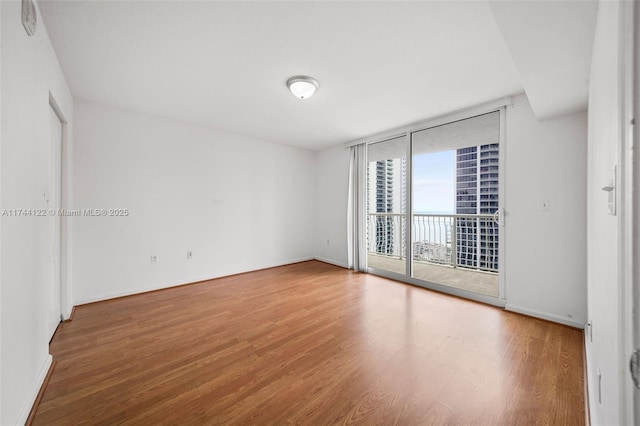 spare room featuring expansive windows and hardwood / wood-style flooring