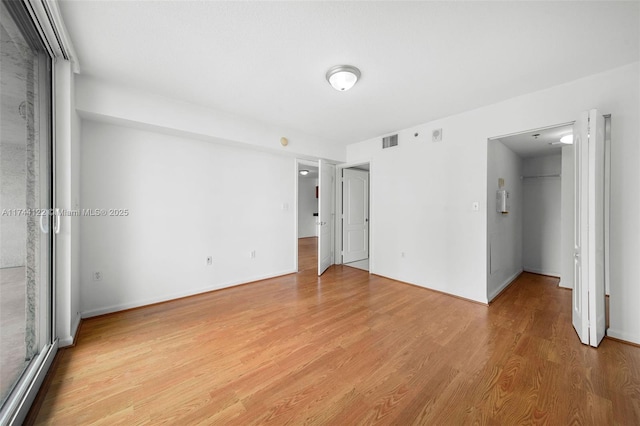 unfurnished bedroom featuring light hardwood / wood-style flooring, a walk in closet, and a closet