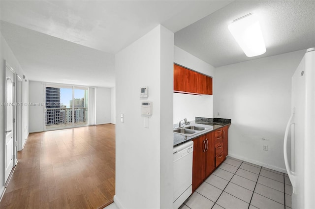 kitchen featuring white appliances, light hardwood / wood-style floors, sink, and a textured ceiling