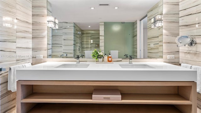 bathroom featuring a shower with door, vanity, and tile walls