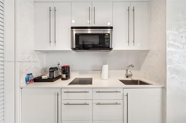 2201 Collins Ave Unit 811, Miami Beach, FL 33139 - kitchen with stainless steel microwave, a sink, white cabinets, and black electric stovetop