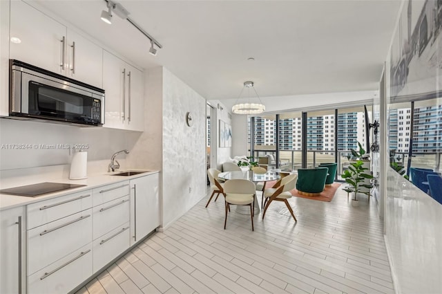 2201 Collins Ave Unit 811, Miami Beach, FL 33139 - kitchen with stainless steel microwave, a sink, black electric cooktop, light countertops, and white cabinets