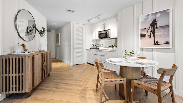 kitchen with white cabinetry, track lighting, and light parquet flooring