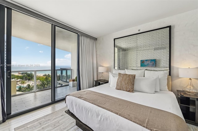 2201 Collins Ave Unit 811, Miami Beach, FL 33139 - bedroom featuring expansive windows, a water view, access to exterior, and wood finished floors