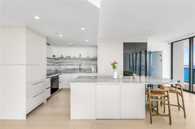 kitchen featuring white cabinets, light countertops, backsplash, a center island, and modern cabinets