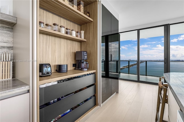 kitchen featuring a water view, light wood-style floors, expansive windows, open shelves, and modern cabinets