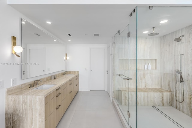 full bath with visible vents, a sink, a marble finish shower, and double vanity