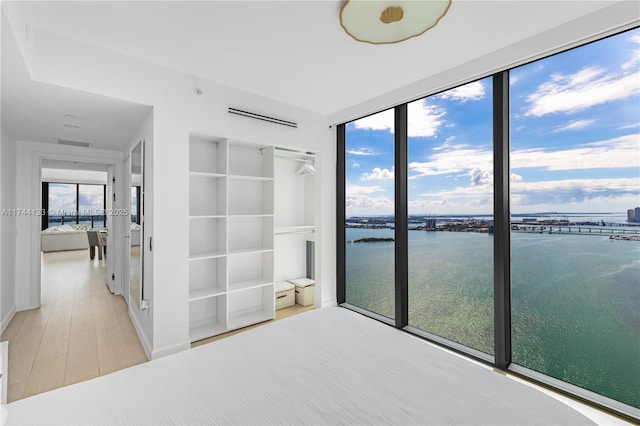 unfurnished bedroom featuring a water view, wood finished floors, and visible vents