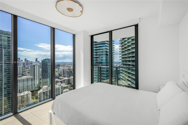 bedroom featuring expansive windows, access to outside, and a view of city