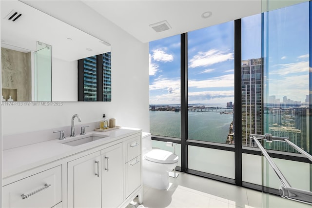 bathroom with a city view, floor to ceiling windows, a water view, toilet, and vanity