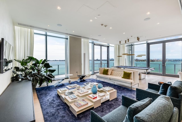 living room with expansive windows, french doors, a water view, and recessed lighting