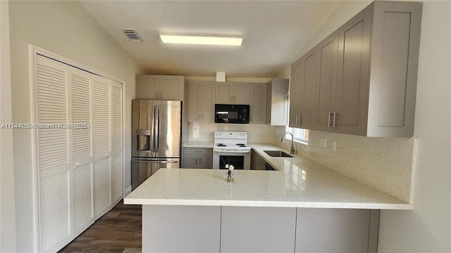 kitchen with electric range, kitchen peninsula, and stainless steel refrigerator with ice dispenser