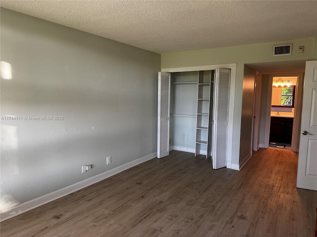 unfurnished bedroom with dark hardwood / wood-style floors, a closet, and a textured ceiling