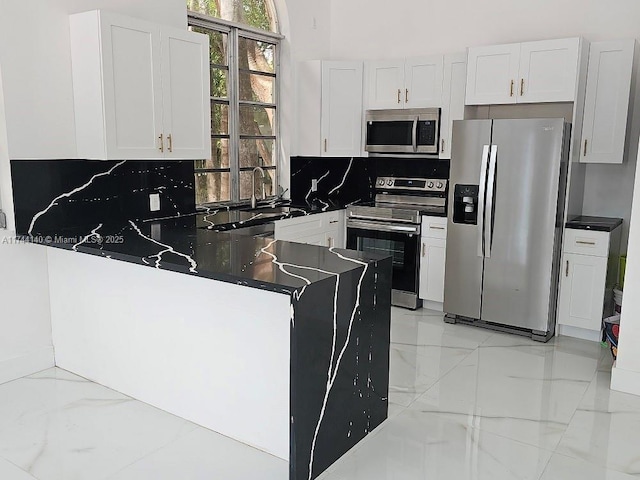 kitchen with stainless steel appliances, tasteful backsplash, white cabinets, and kitchen peninsula