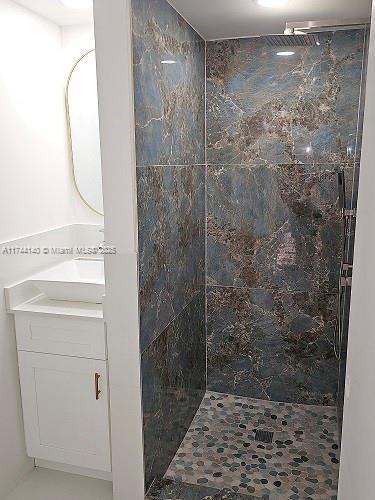 bathroom with vanity and tiled shower