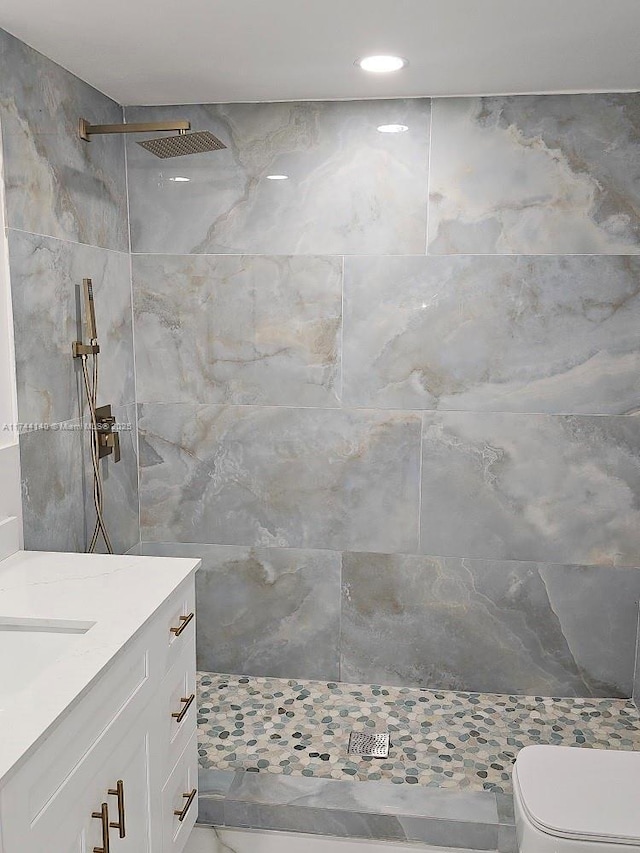 bathroom with vanity, a tile shower, and toilet