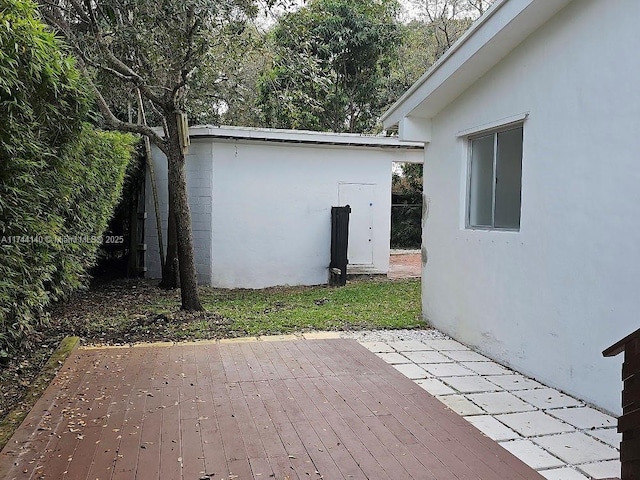 wooden terrace with a patio and a storage unit