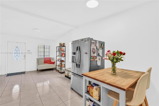 kitchen featuring stainless steel refrigerator with ice dispenser, lofted ceiling with beams, and light tile patterned floors