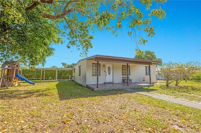 view of front of home featuring a patio, a playground, and a front lawn