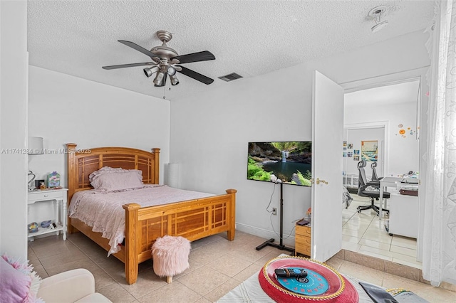 bedroom with tile patterned flooring, ceiling fan, and a textured ceiling