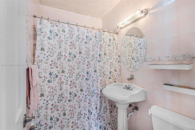 bathroom featuring walk in shower, tile walls, and toilet