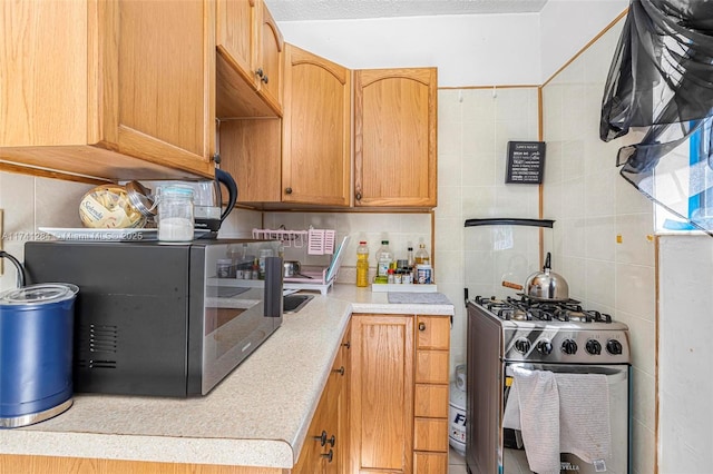 kitchen featuring tile walls, stainless steel gas range, and decorative backsplash