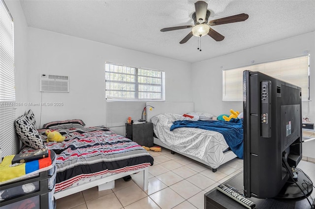 tiled bedroom featuring ceiling fan, a wall mounted air conditioner, and a textured ceiling