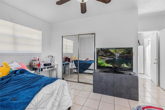 bedroom featuring ceiling fan, a textured ceiling, a closet, and light tile patterned floors