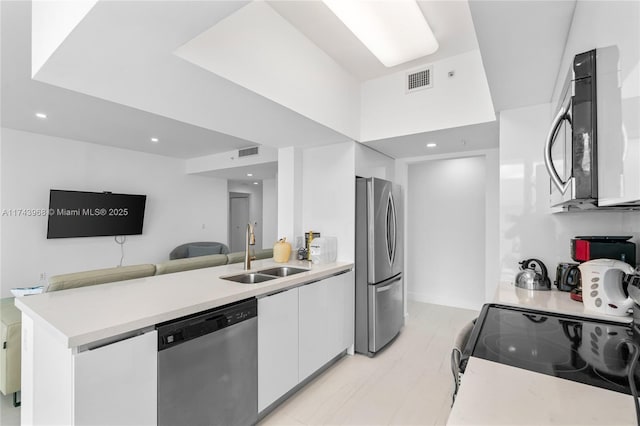 kitchen with appliances with stainless steel finishes, sink, and white cabinets