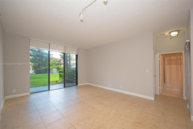 3300 NE 192nd St Unit 111, Aventura, FL 33180 - spare room featuring expansive windows, a textured ceiling, light tile patterned floors, and baseboards