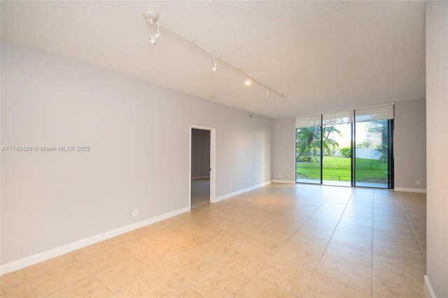 3300 NE 192nd St Unit 111, Aventura, FL 33180 - unfurnished room with light tile patterned floors, floor to ceiling windows, baseboards, and a textured ceiling