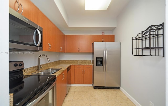 3300 NE 192nd St Unit 111, Aventura, FL 33180 - kitchen featuring stainless steel appliances, a sink, light stone counters, brown cabinets, and light tile patterned floors